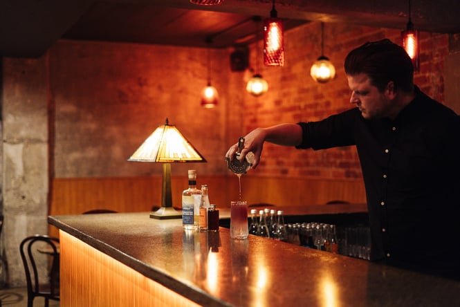 Bartender making a cocktail in the low light of Bar Magda in Auckland