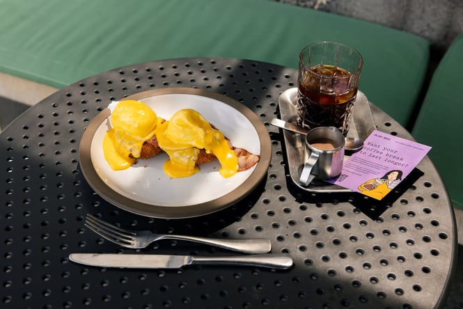 Close up of breakfast at Ozone including a plate of eggs benedict and iced coffee