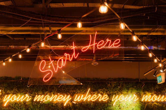 A fluorescent sign that says 'Start Here'.