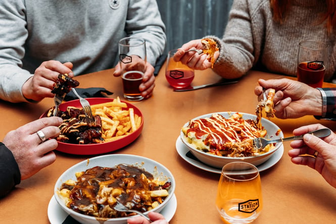 People sitting around bowls of loaded fries.