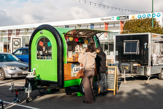 Two customers line up at a green food truck at Pop Up Eats.
