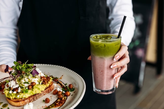 Cafe staff holding smashed avo and strawberry matcha.