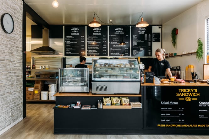 Staff working behind the black counter at Tricky's Sandwich Co.