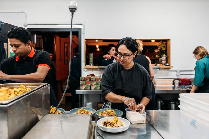 Two people working in the kitchen in Everybody Eats.