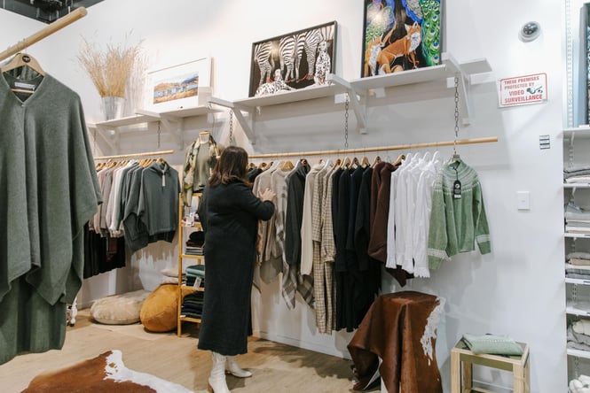 A lady shopping looking at racks of clothing in riversides Shopology store.