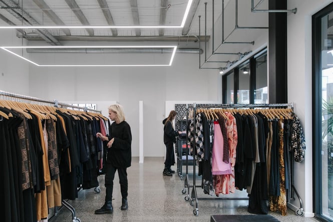 A lady in all black clothing looking through the clothing racks at Plume Christchurch.