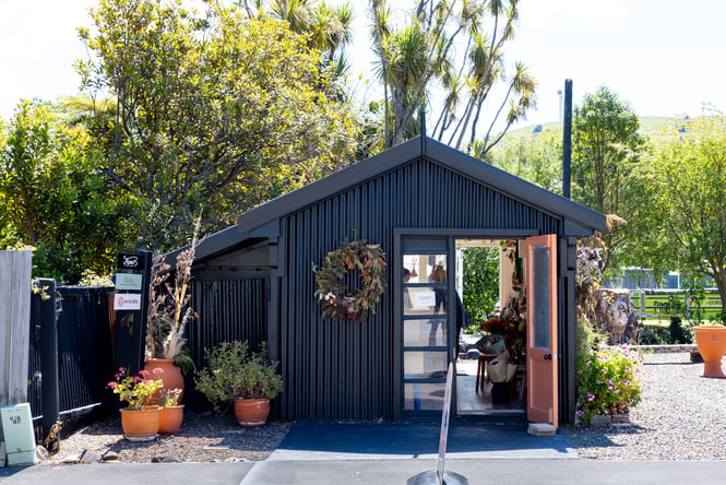 Exterior black shed boutique with floral wreath at entrance