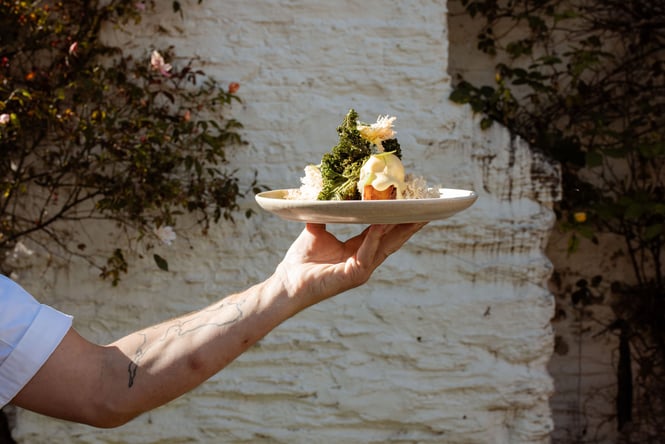 Chef holding up plate of refined eggs benedict at Dishery in Arrowtown