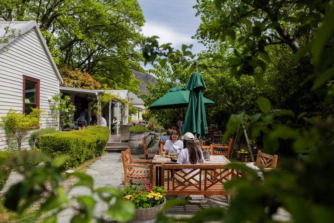 Customers sitting in the garden at an outdoor table at Provisions of Arrowtown.