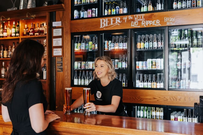 Women handing two pints over to a customer at Dux Central.