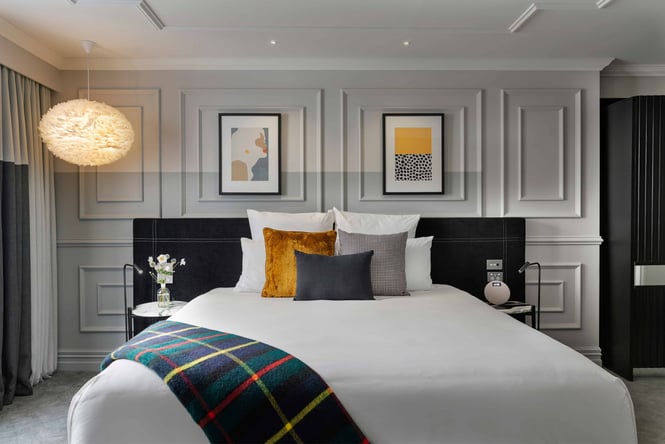 A white bed decorated in Scottish fabrics.
