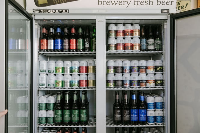Bottles and cans of beer on display inside a fridge.