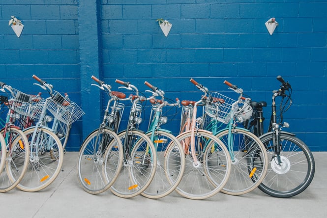 City commuter bikes lined up next to each other in front of a bright blue wall