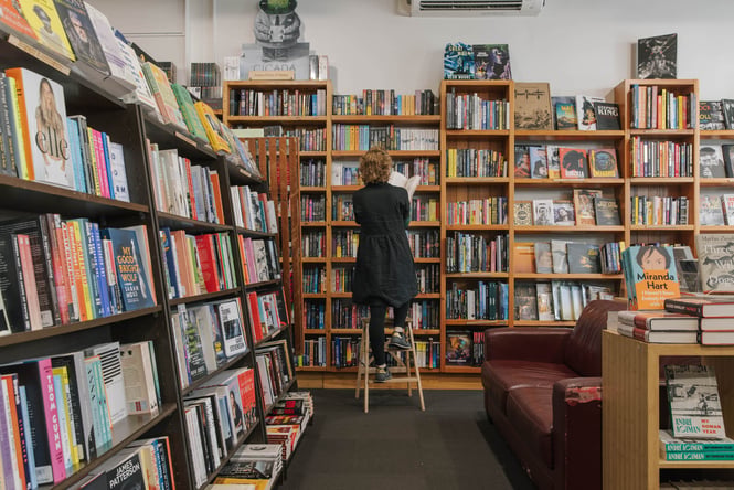 Someone on ladder getting a book from the shelf at Scorpio Books in Christchurch