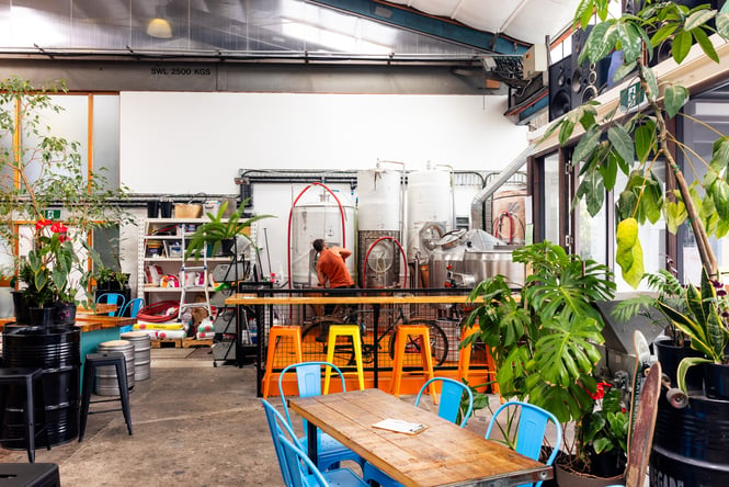 Renegade Brewing's colourful taproom with man brewing by large silver beer tanks