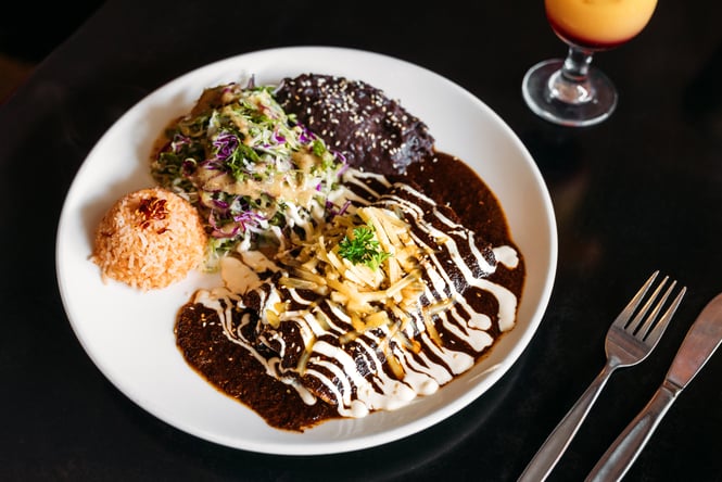 A Mexican meal on a plate on a dark table.