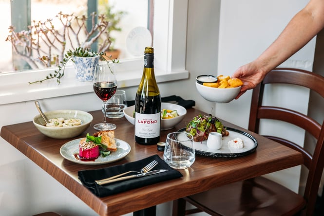 Dishes and bottle of wine on the table at Rata's Kitchen.