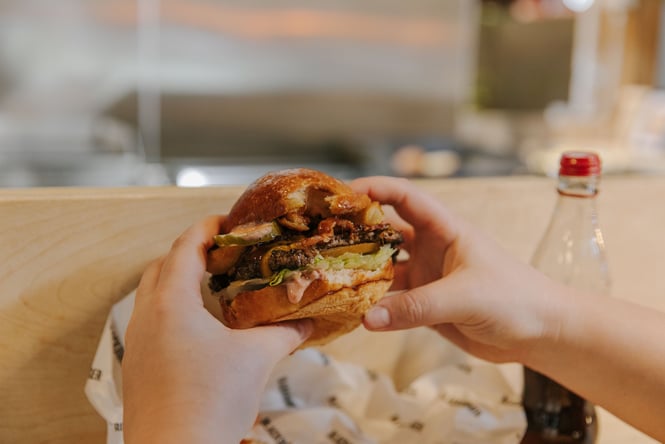 Close up of hands holding onto a burger.