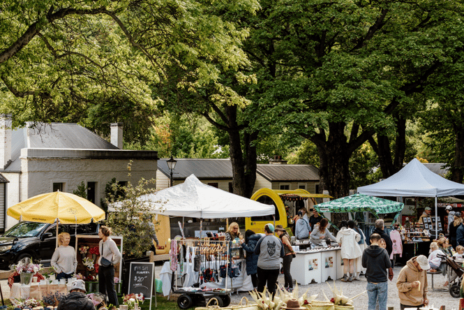 People walking around a farmers market on a sunny day.