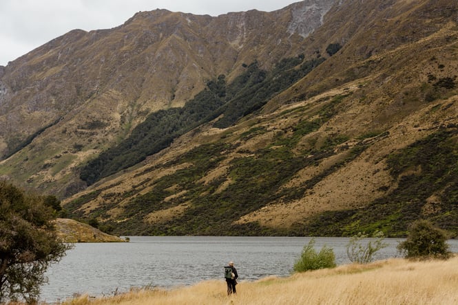 A person walking a track by a lake.
