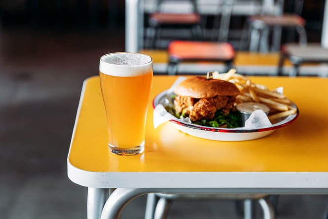 A burger and a pint on a table.