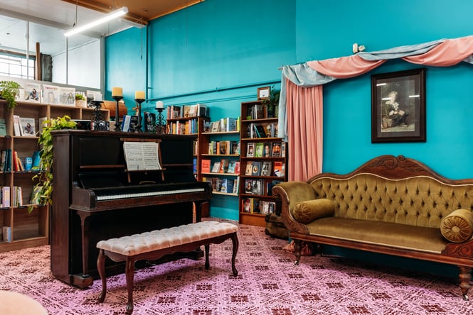 Sofa set up next to a piano with bookshelves behind.