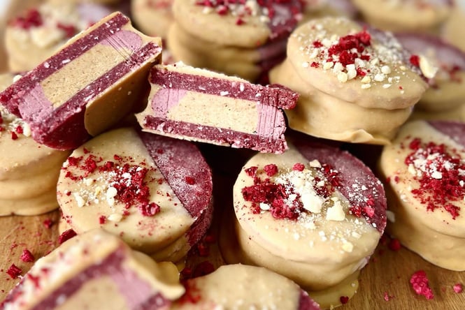 A close up of pink and white biscuits pilled up on a chopping board.