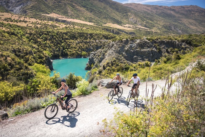 Three people biking on a track on a sunny day.