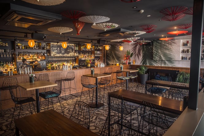 An interior view of the Parasol & Swing bar where a bartender is preparing drinks.