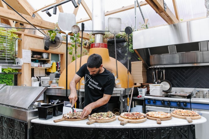 A man cutting a pizza in a restaurant.