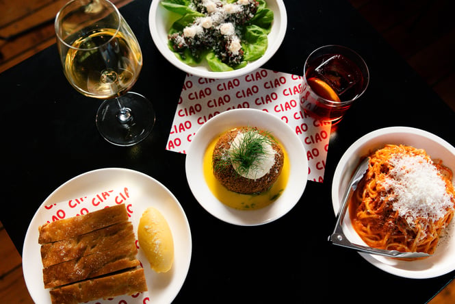 Flat lay of Italian dishes at Ciao including spaghetti, arancini, focaccia and a negroni