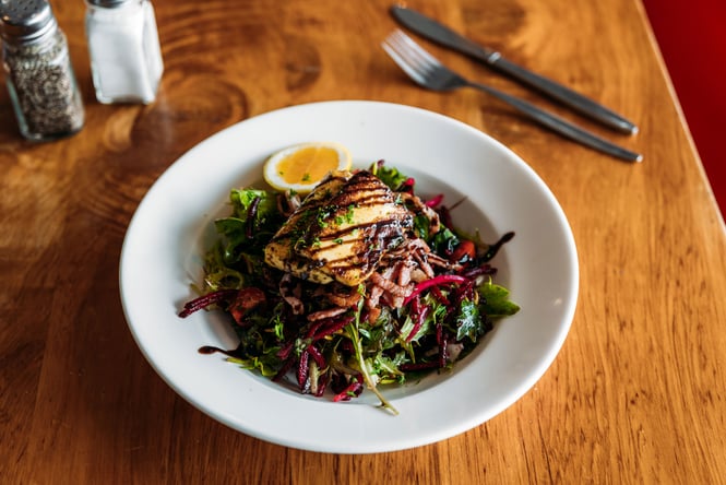 Grilled halloumi on salad in a bowl.