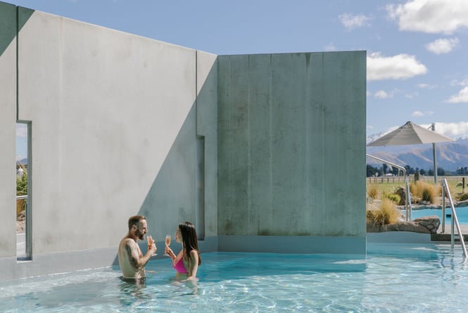 A man and woman drinking champagne in the pool.