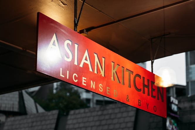 A red 'Asian Kitchen' building sign at night.