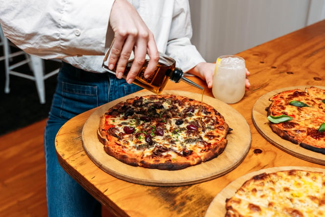 Oil being poured onto a cooked pizza.