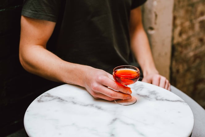 A hand holding a cocktail.
