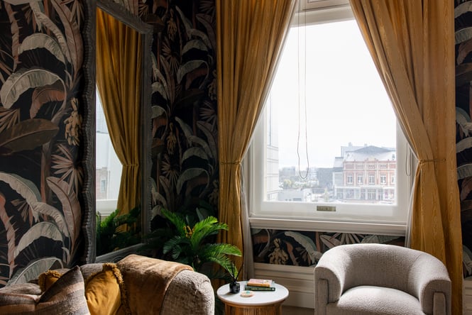 Armchairs inside The Eve Apartment room with city views out the window