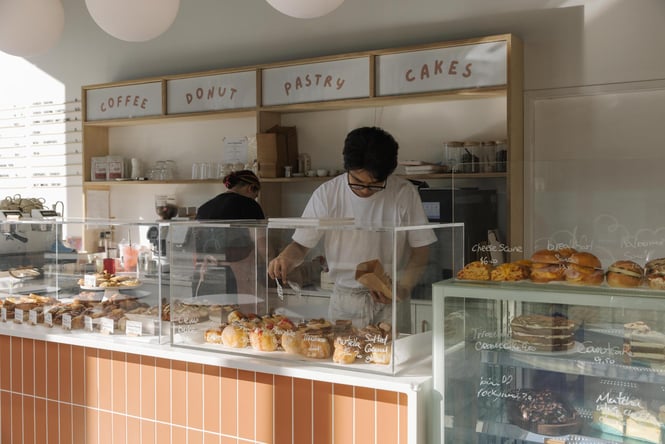 Person reaching into cabinet for a donut at Fluffy Bake Shop in Christchurch