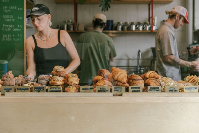A cabinet full of pastries with three staff members in the background