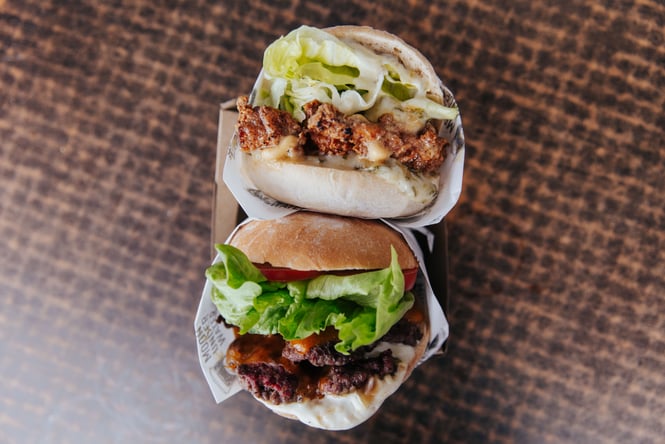 A close up of two burgers on a table.
