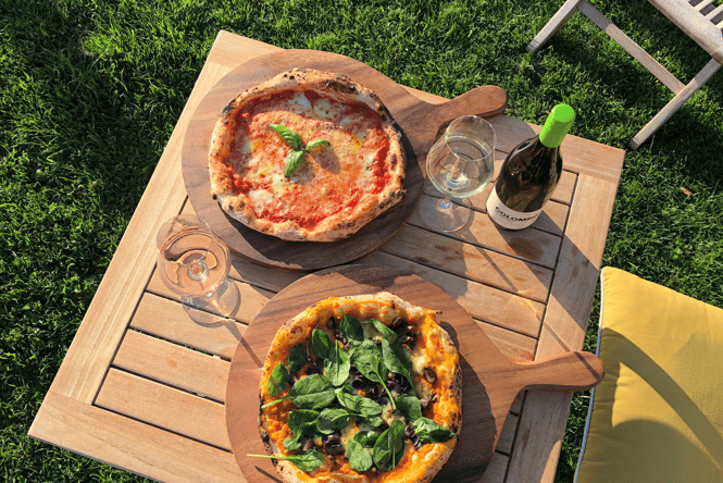 A flatly of Pizza and wine on a table at Colombo.