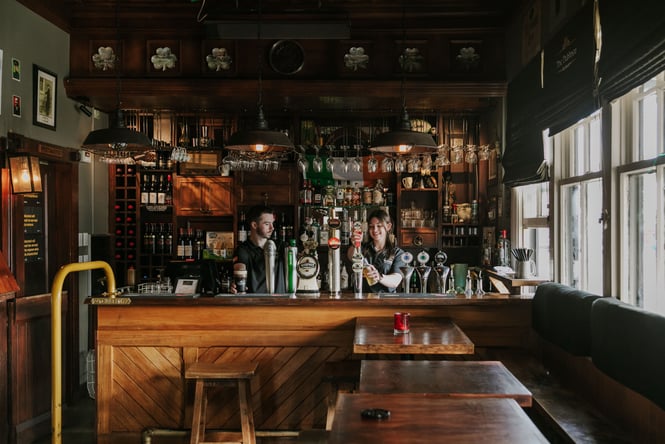 Two staff member standing behind the bar at The Dubliner.