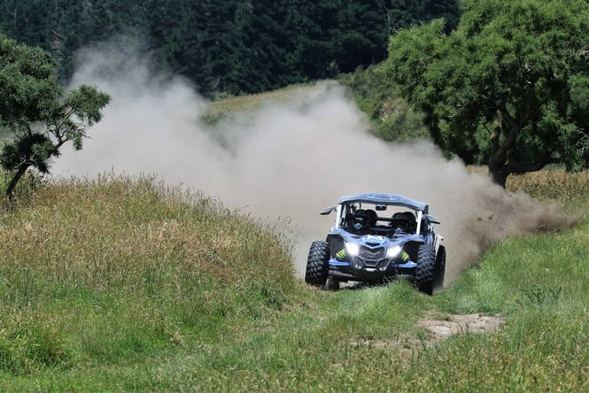 A small kart driving over a grassy hill.