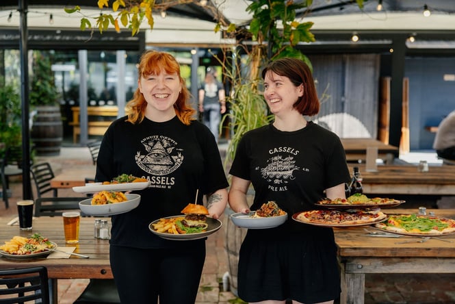 Restaurant staff holding pizzas at The Brewery Bar & Restaurant.