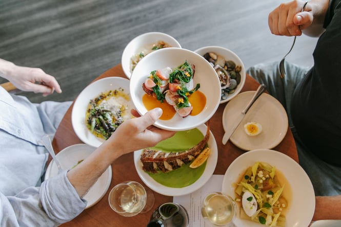 A hand passing a plate of food across a table at Gatherings.