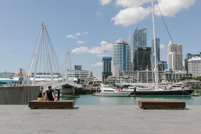 A man and a woman sitting on a bench at the Auckland waterfront.