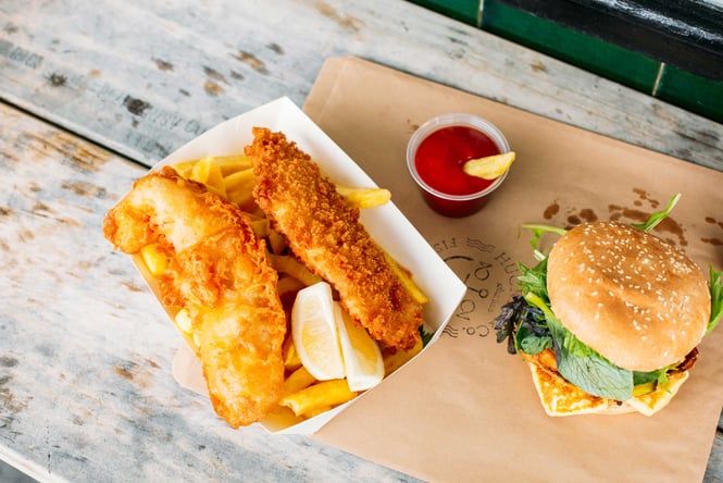 Close up of fish and chips and burgers on a table.