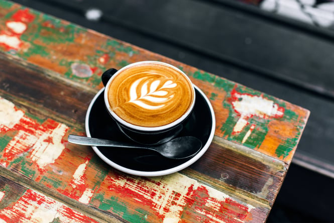 A coffee sitting on a painted table.