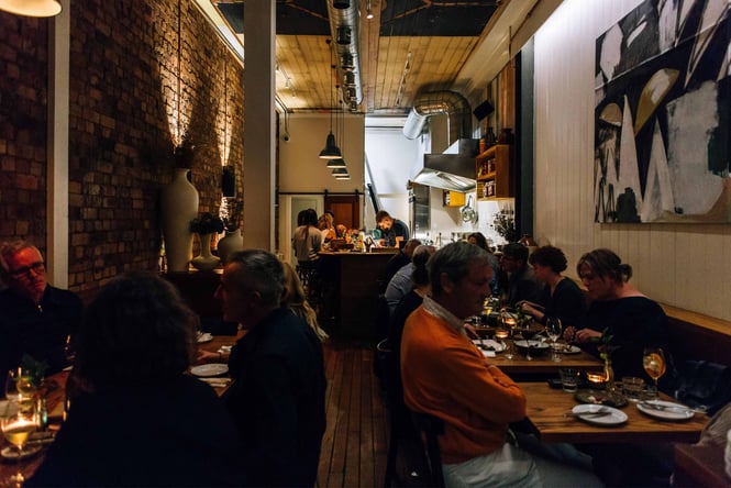 People dining inside a busy bar at night.