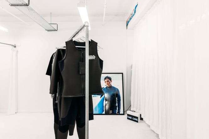 Black clothes on display inside a white retail store.